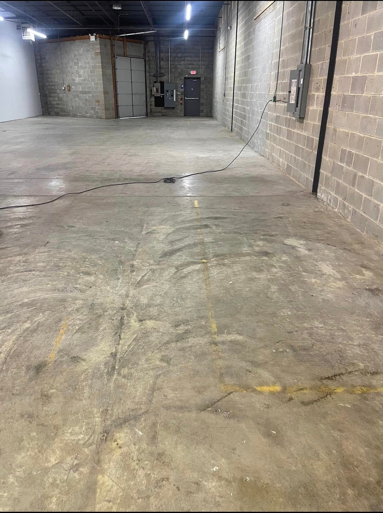 A large empty warehouse with a concrete floor and brick walls.