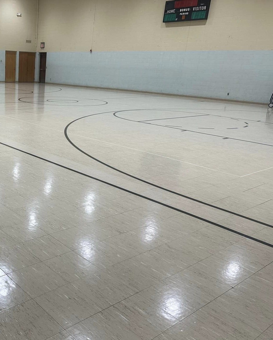 An empty basketball court with a scoreboard above it