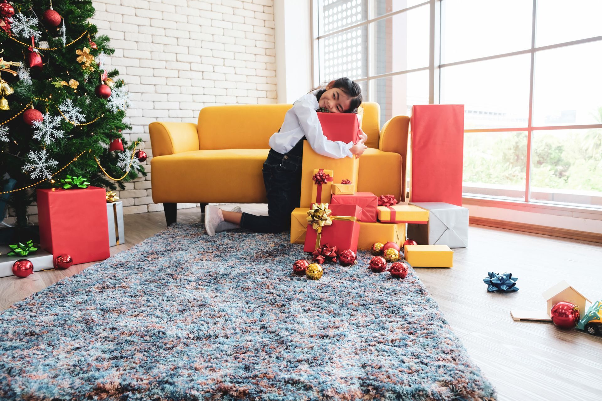 A man is sitting on a couch surrounded by christmas presents.