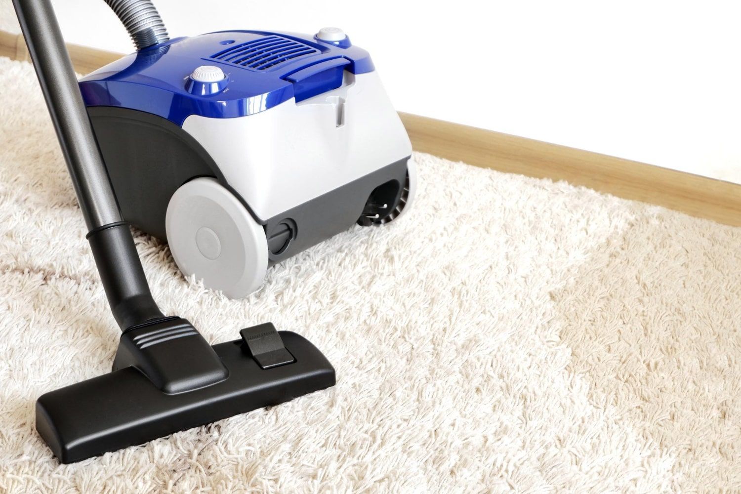 A vacuum cleaner is sitting on top of a white carpet.