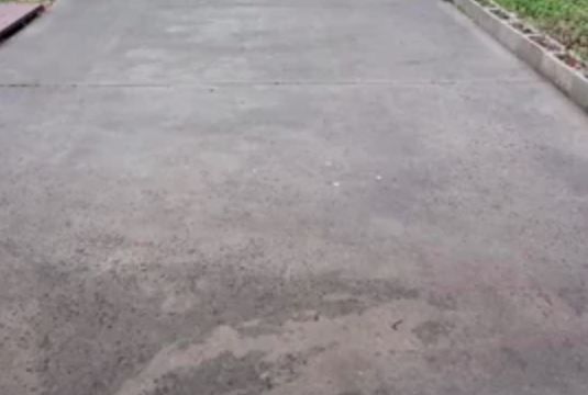 A person is walking down a sidewalk in a park.