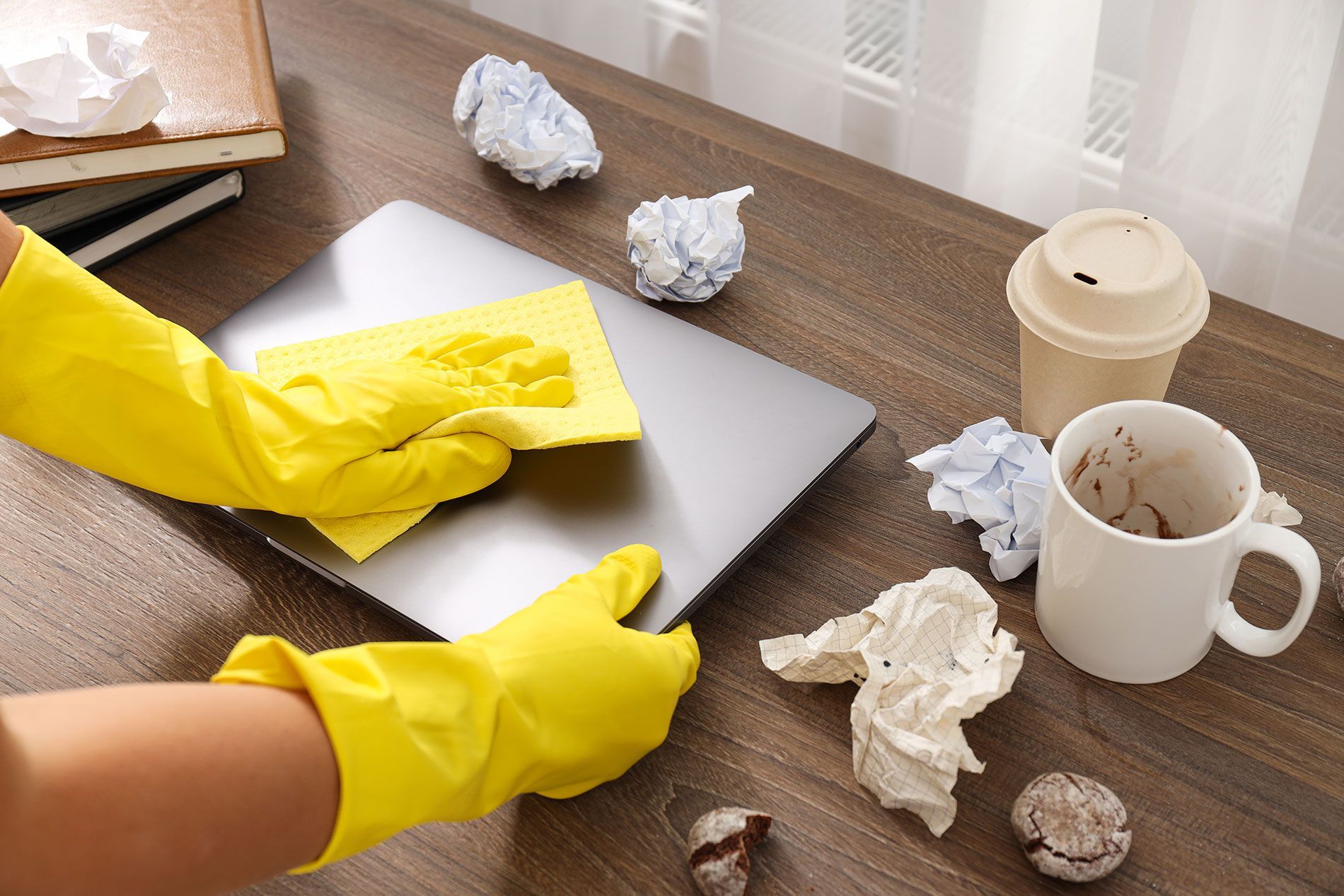 A person wearing yellow gloves is cleaning a laptop computer.