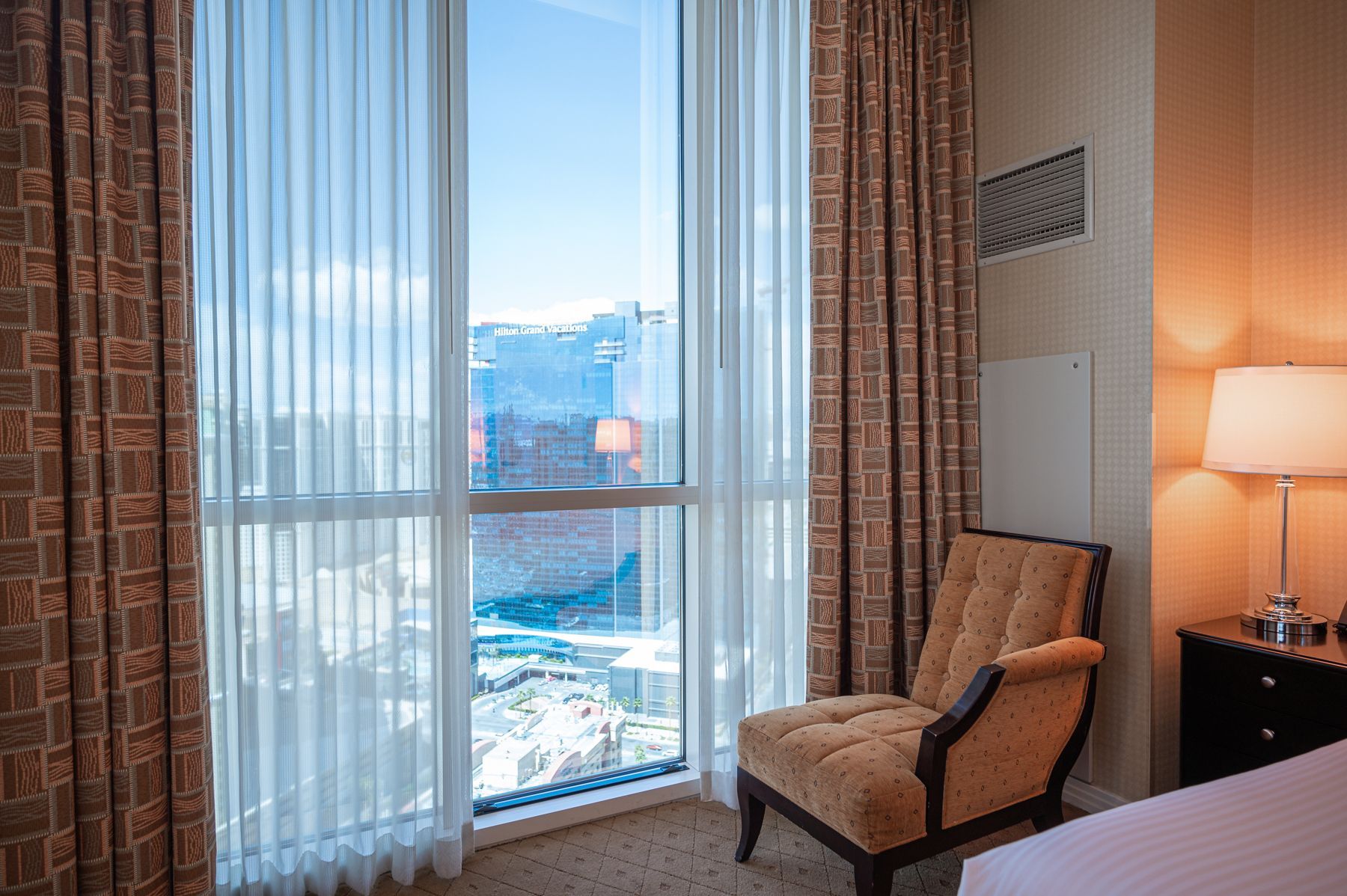 Hotel room with chair, lamp, and large window overlooking snowy mountains