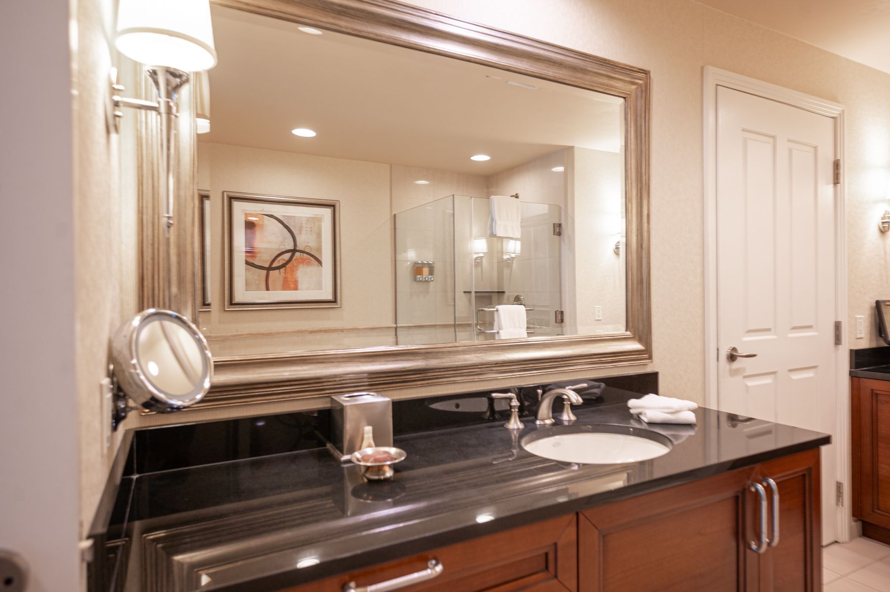 Elegant bathroom vanity with large mirror, black countertop, and sink in a warm beige interior
