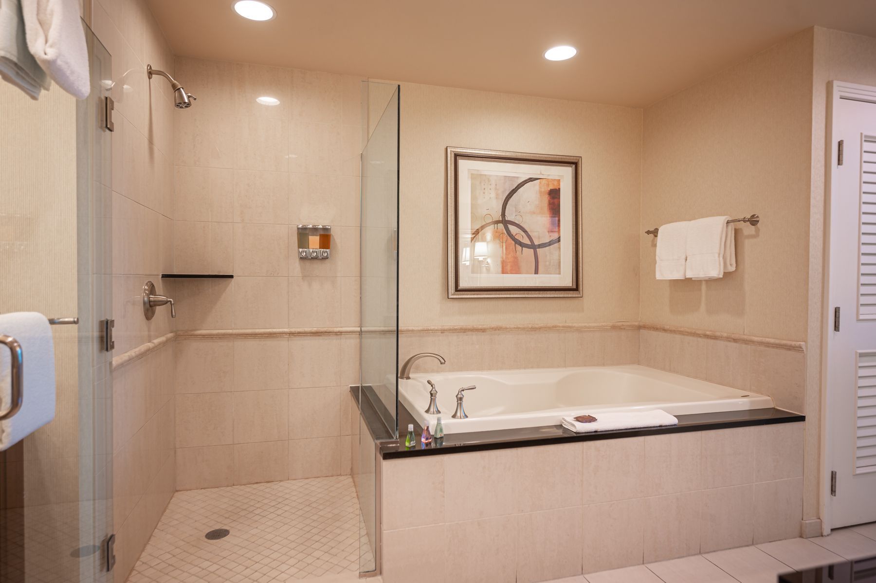 Accessible bathroom with walk-in shower, bathtub, and beige tiled walls