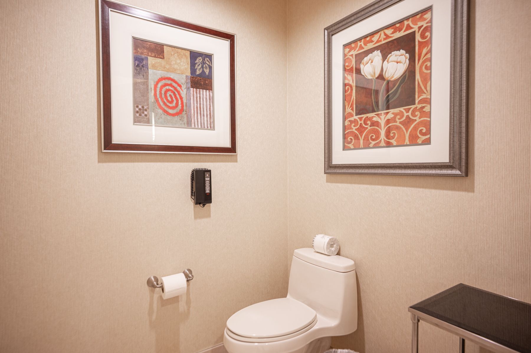 Small bathroom with toilet, wall art, and beige wallpaper.