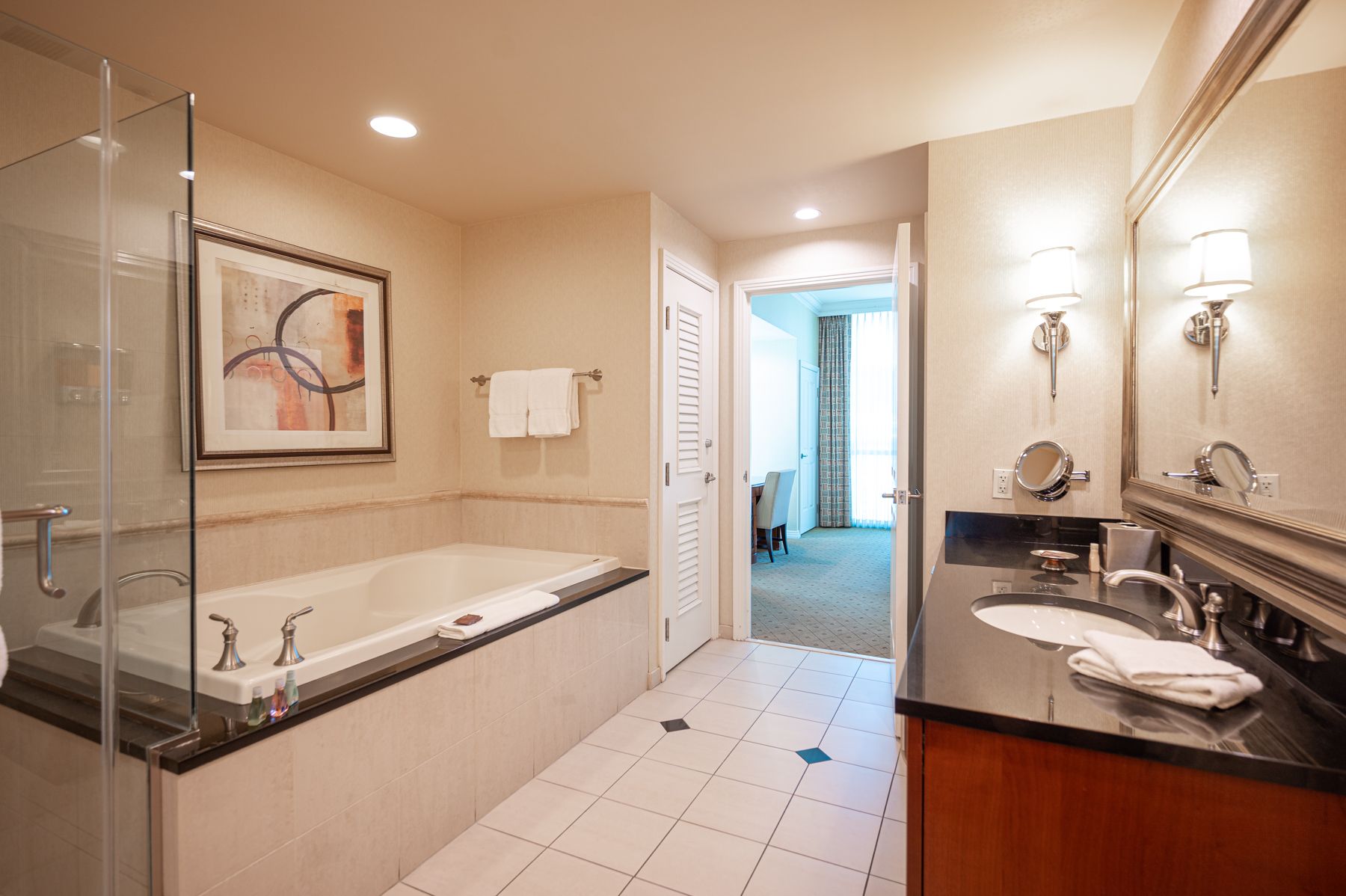 Bright bathroom with a soaking tub, glass shower, double vanity, and marble tile floor.