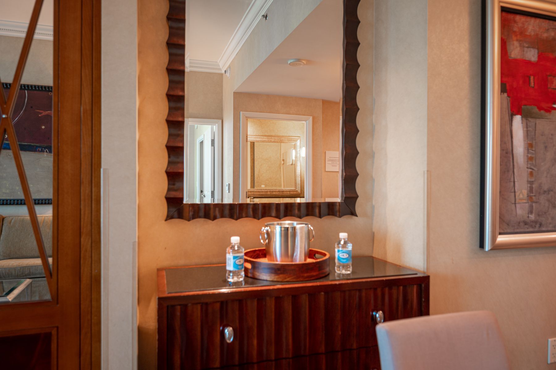 Hallway console table with water bottles, a tray, and a mirror above it