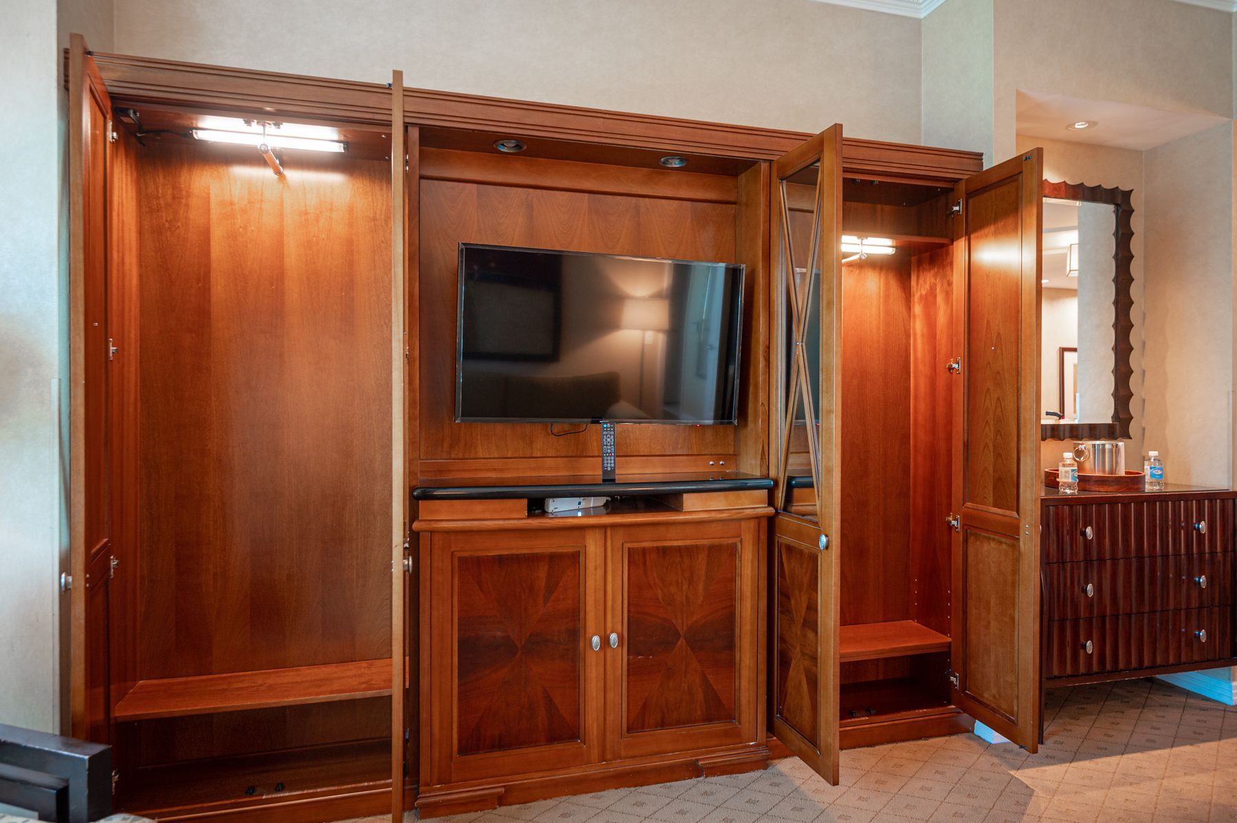 Wooden wall unit with built-in TV, cabinet storage, and lit display shelves in a living room