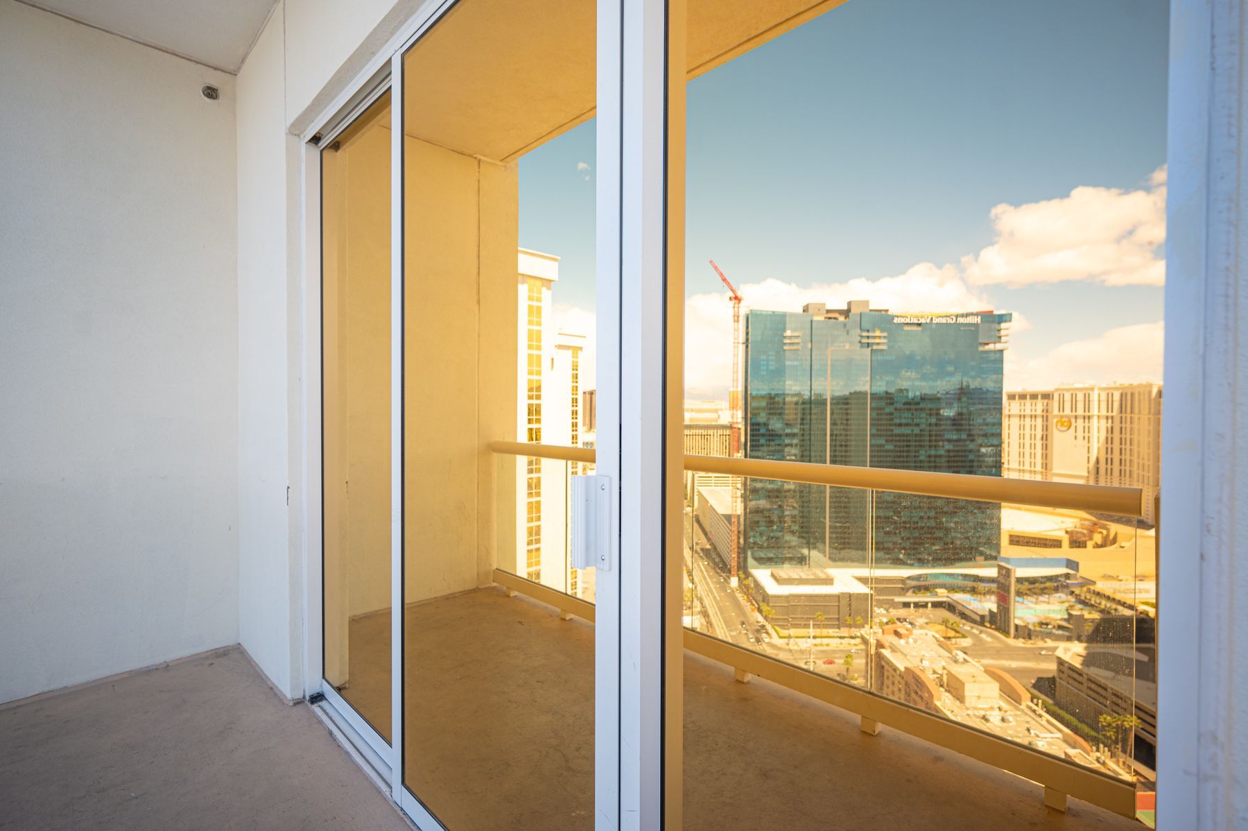 Balcony with sliding glass doors overlooking a sunny city skyline and buildings