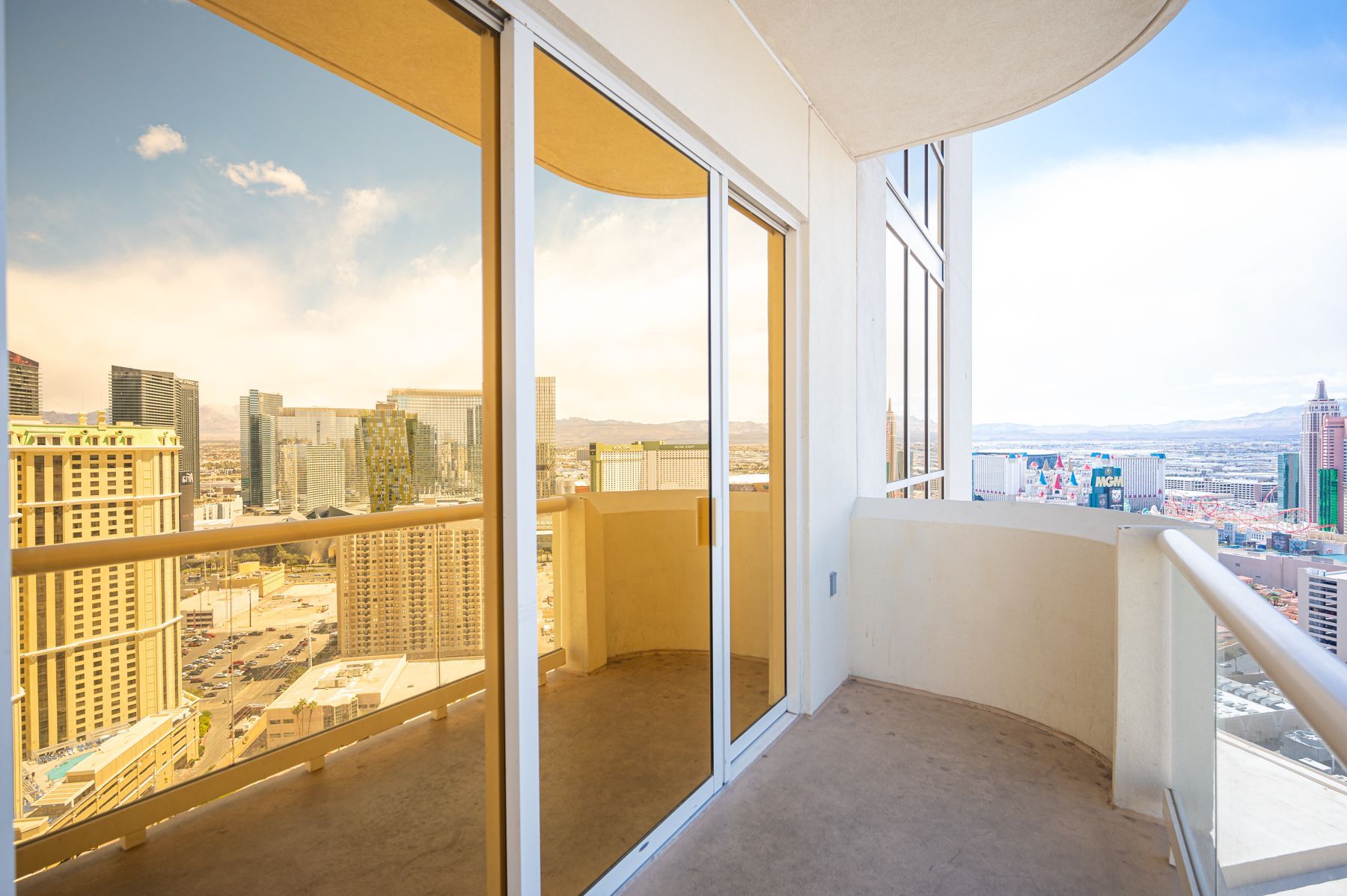 Balcony with sliding glass doors overlooking a sunlit city skyline at sunset