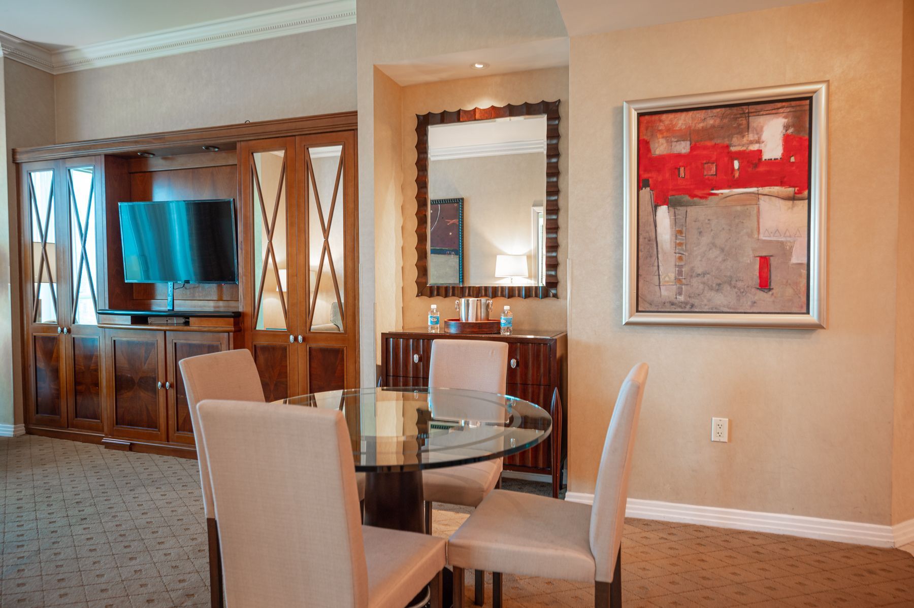 Elegant dining room with glass table, white chairs, wall mirror, and red abstract painting