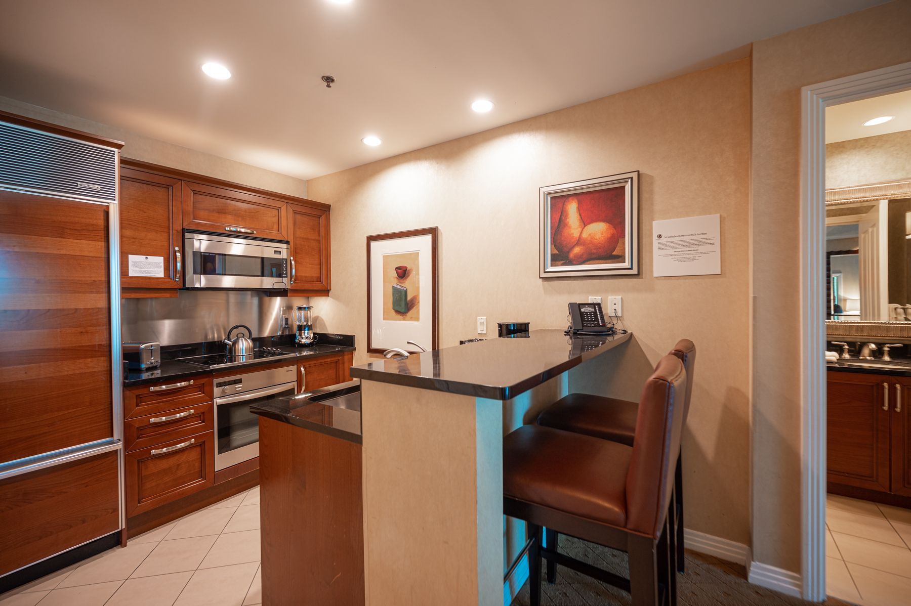 Modern kitchen with bar seating, stainless steel appliances, and warm wood cabinetry