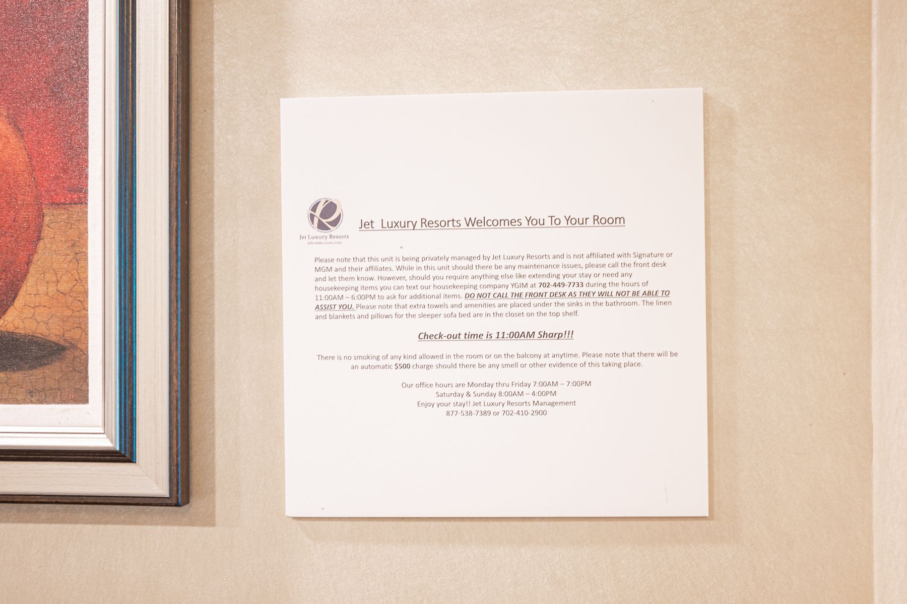 Framed certificate or document mounted on a beige wall beside a framed artwork.