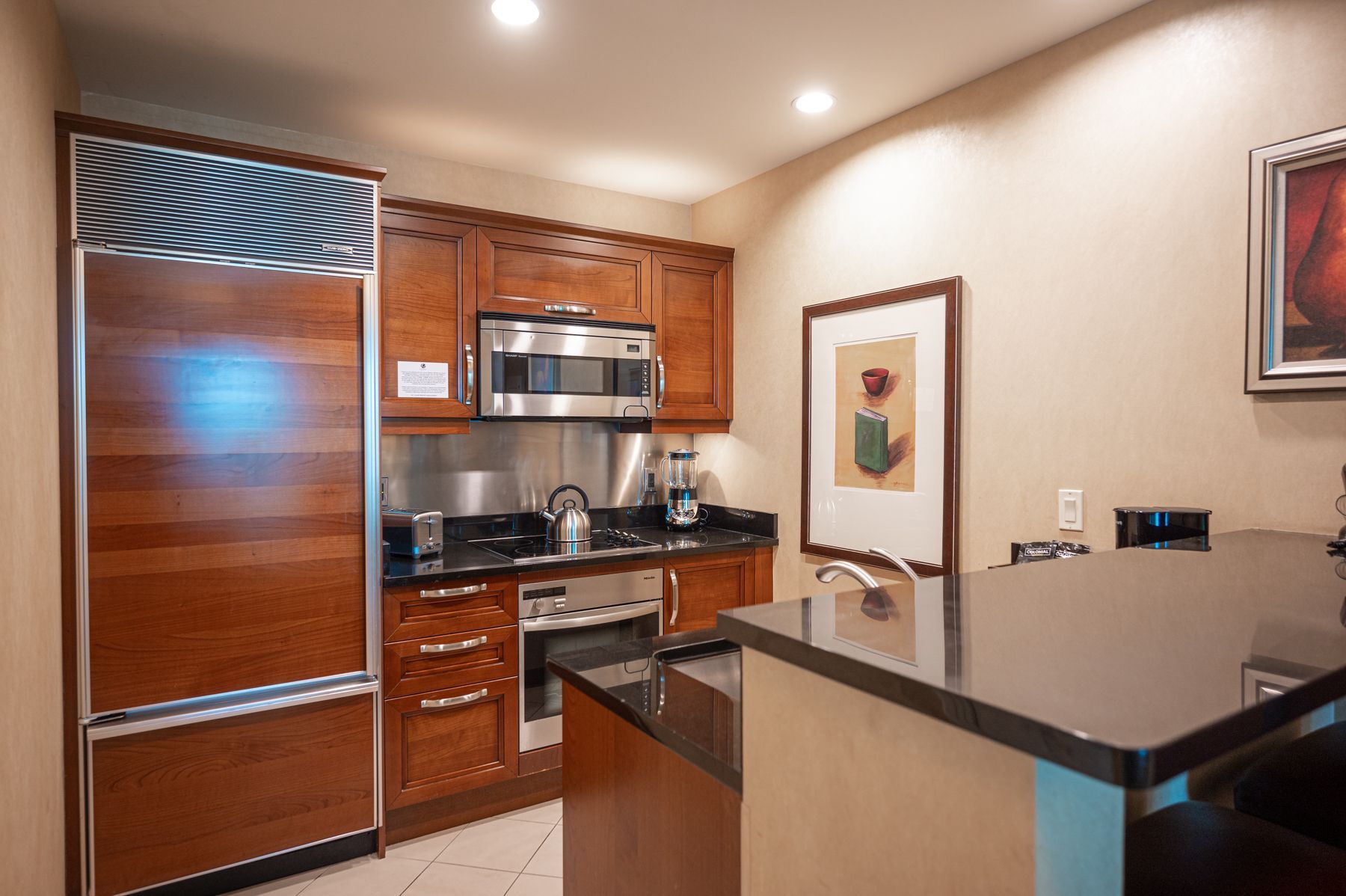 Modern kitchen with wood cabinets, stainless steel appliances, and a dark island countertop