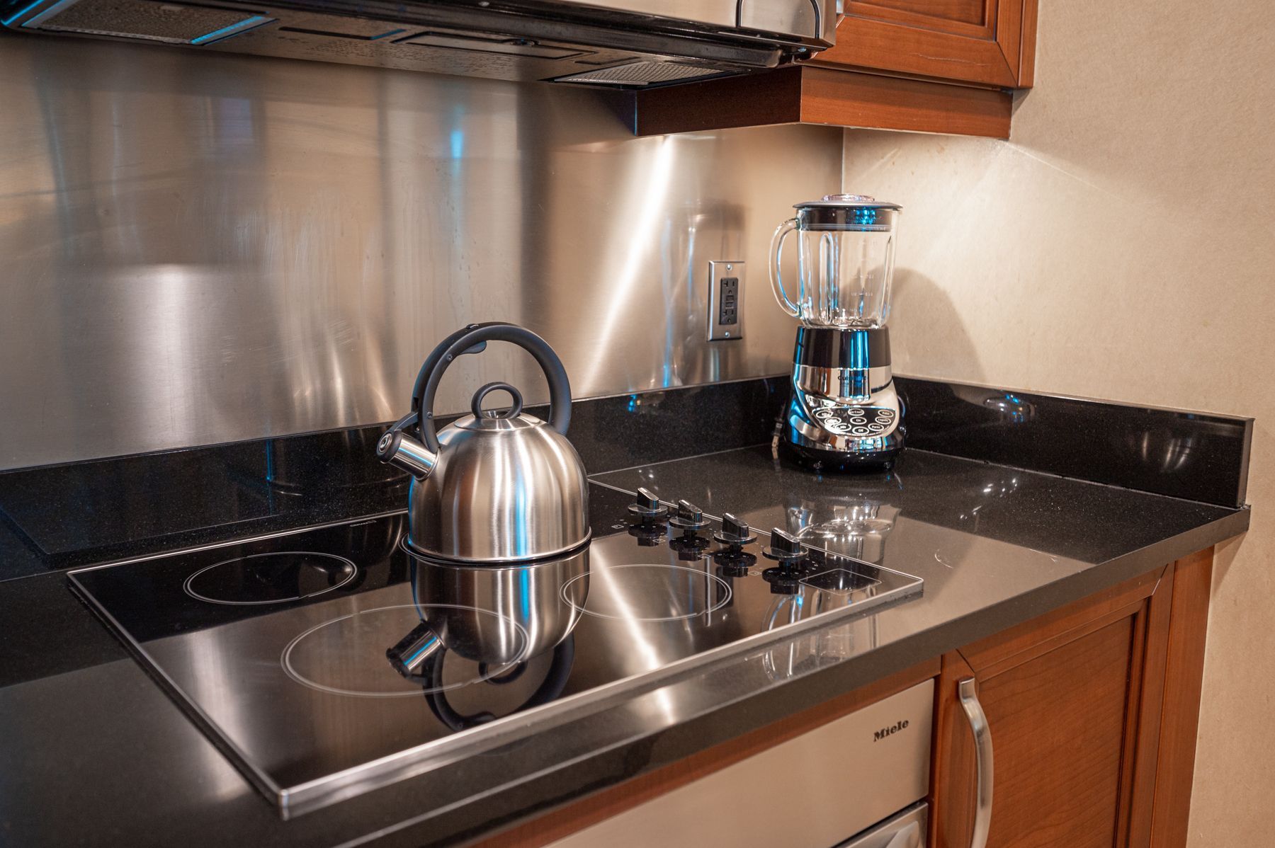 Modern kitchen stove with stainless steel kettle and coffee maker on black countertop