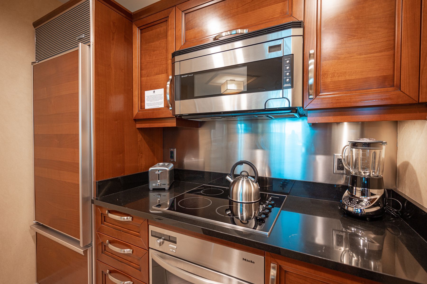 Modern kitchen with stainless steel appliances, dark countertops, and warm wood cabinets