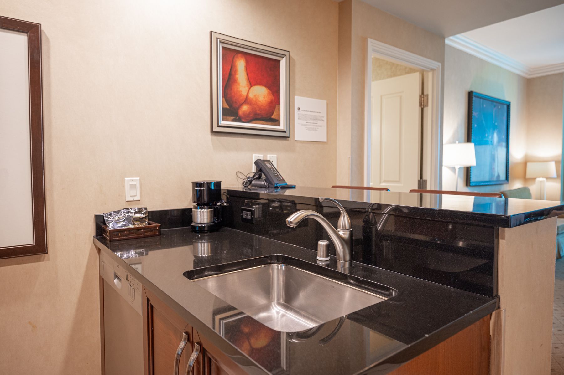 Modern bathroom vanity with black granite countertop, double sinks, and wall art in a hotel-like interior