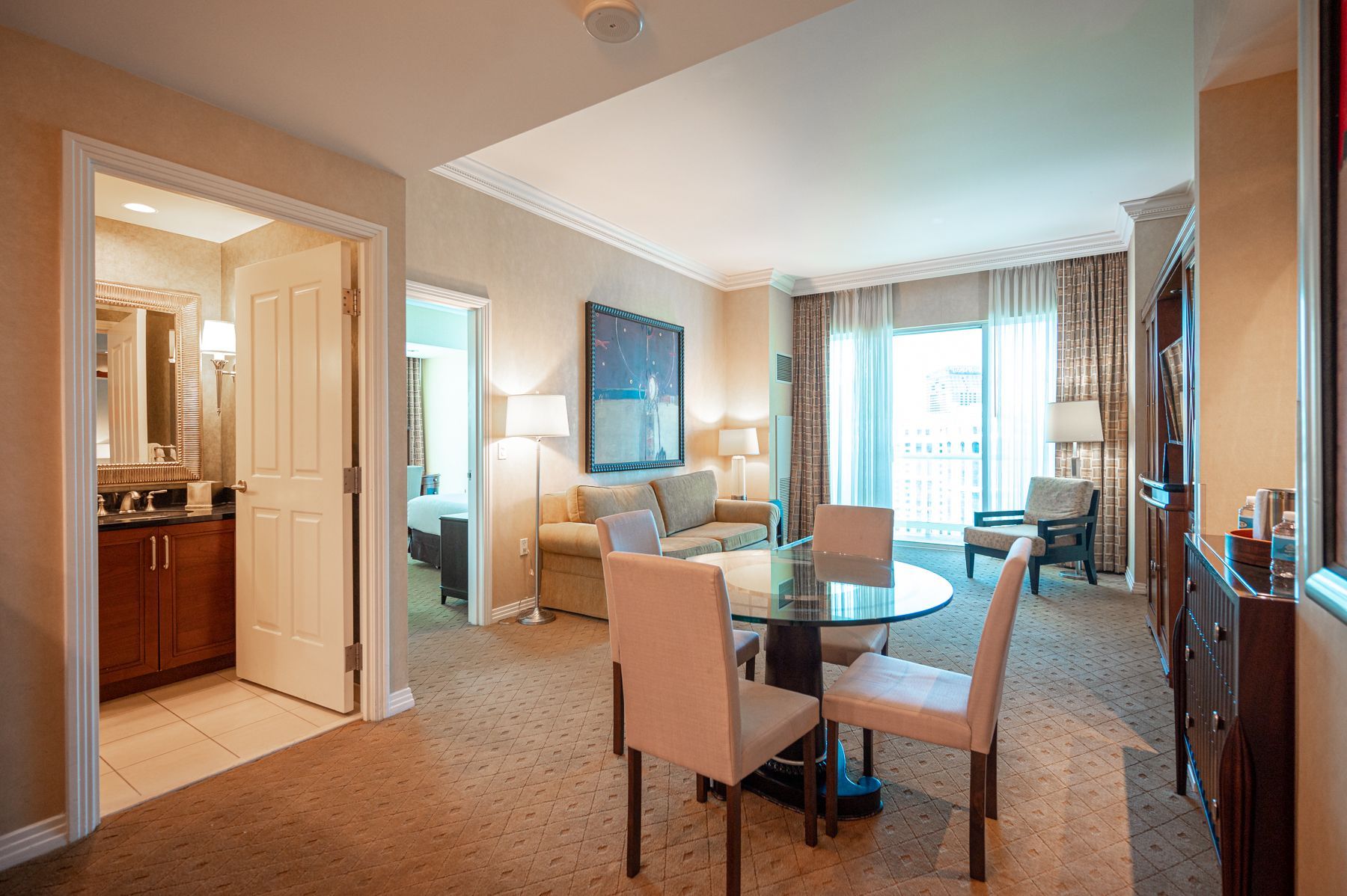 Modern hotel room with dining table, sofa, and bright window view