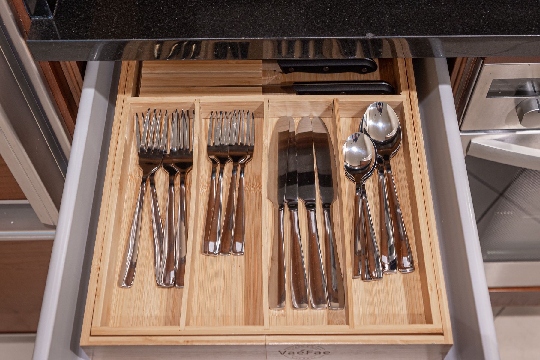 Kitchen drawer with organized silverware and serving spoons in bamboo dividers