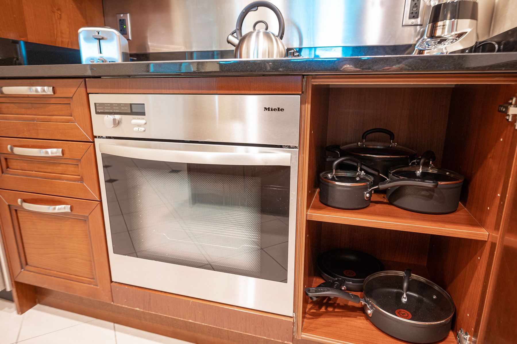 Kitchen cabinets with built-in oven and open shelves holding pots and pans