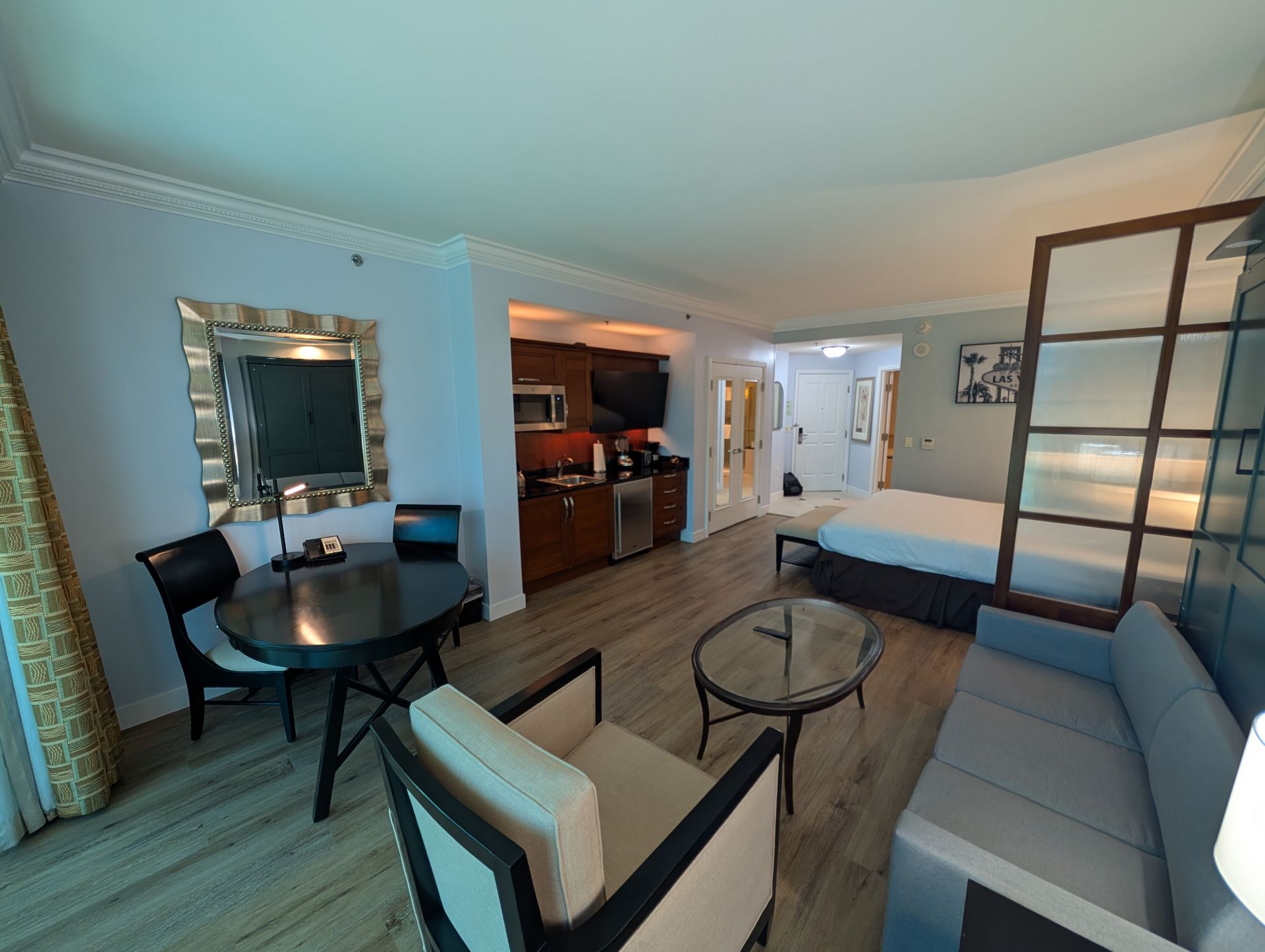 Modern living room with blue walls, sectional sofa, round coffee table, dining nook, and open kitchen view