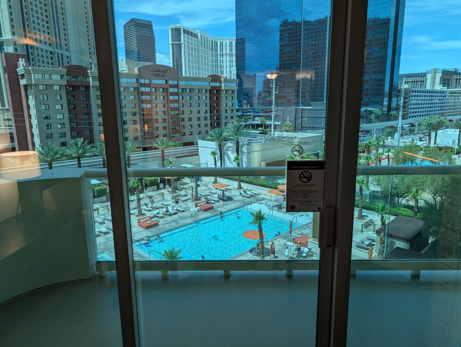 Balcony view of a city pool surrounded by tall buildings and glass towers.
