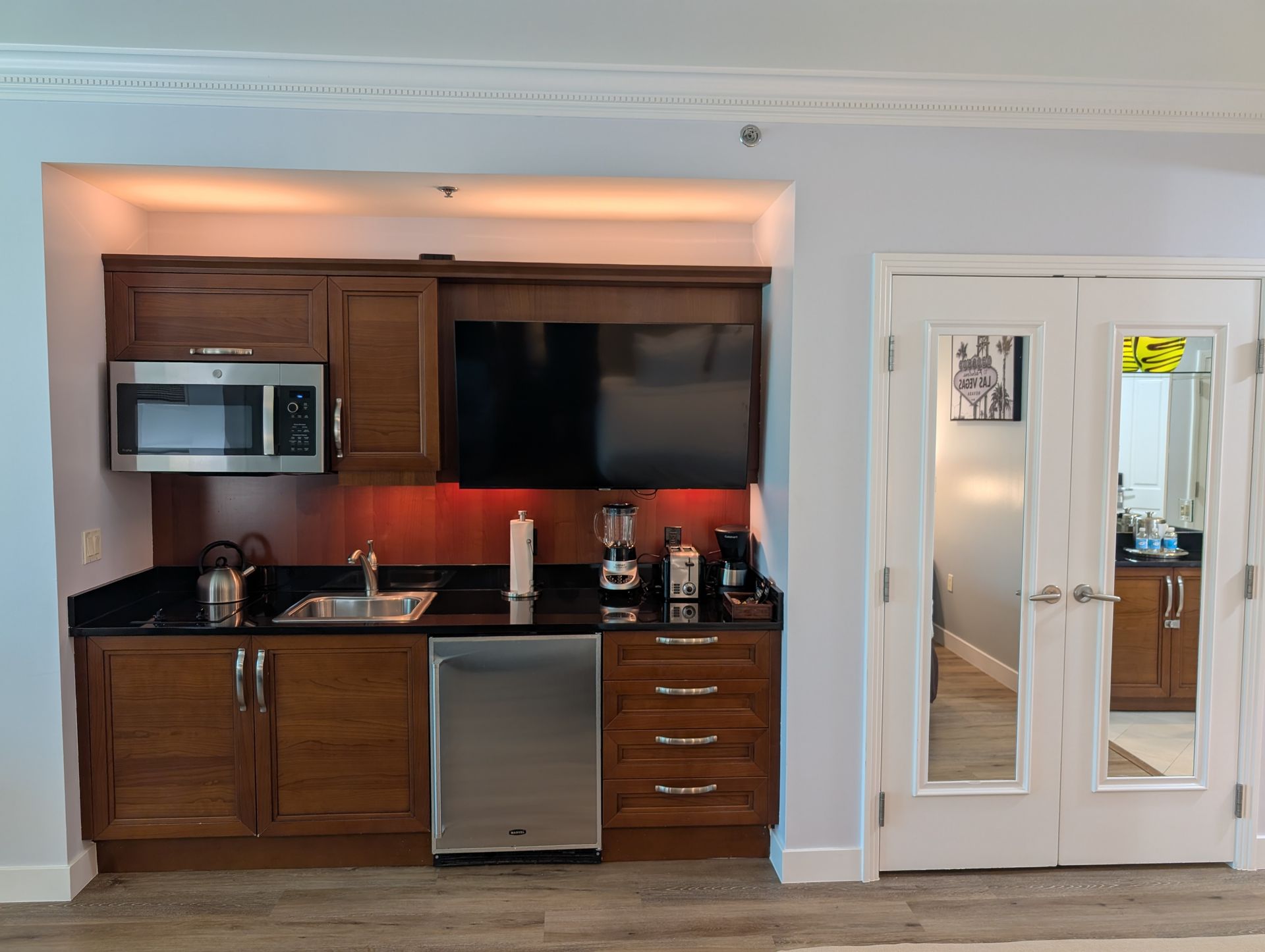 Small kitchen nook with wood cabinets, stainless appliances, black countertop, and white French doors