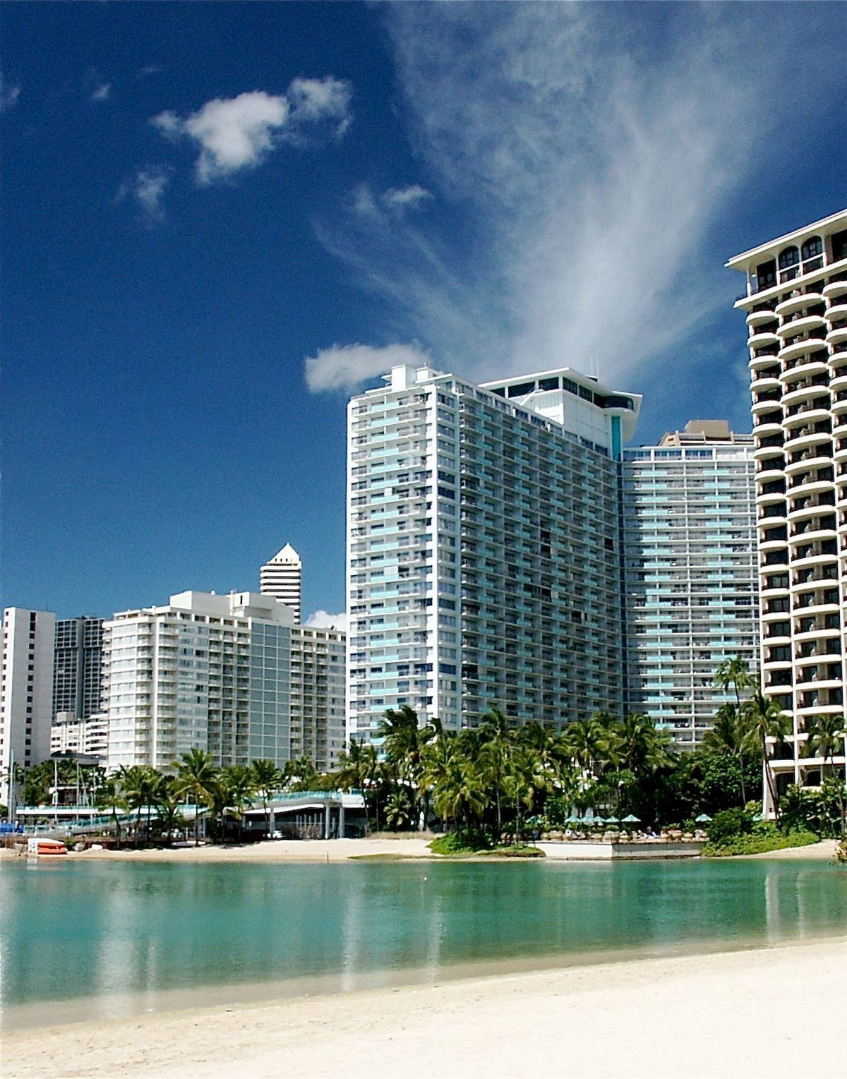 High-rise beachfront condos and hotels along a turquoise bay under a bright blue sky