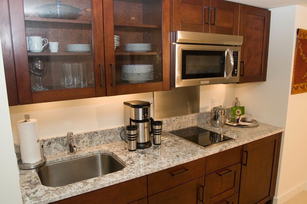 Modern kitchen with wooden cabinets, granite counter, sink, microwave, coffee maker, and stainless sink fixture