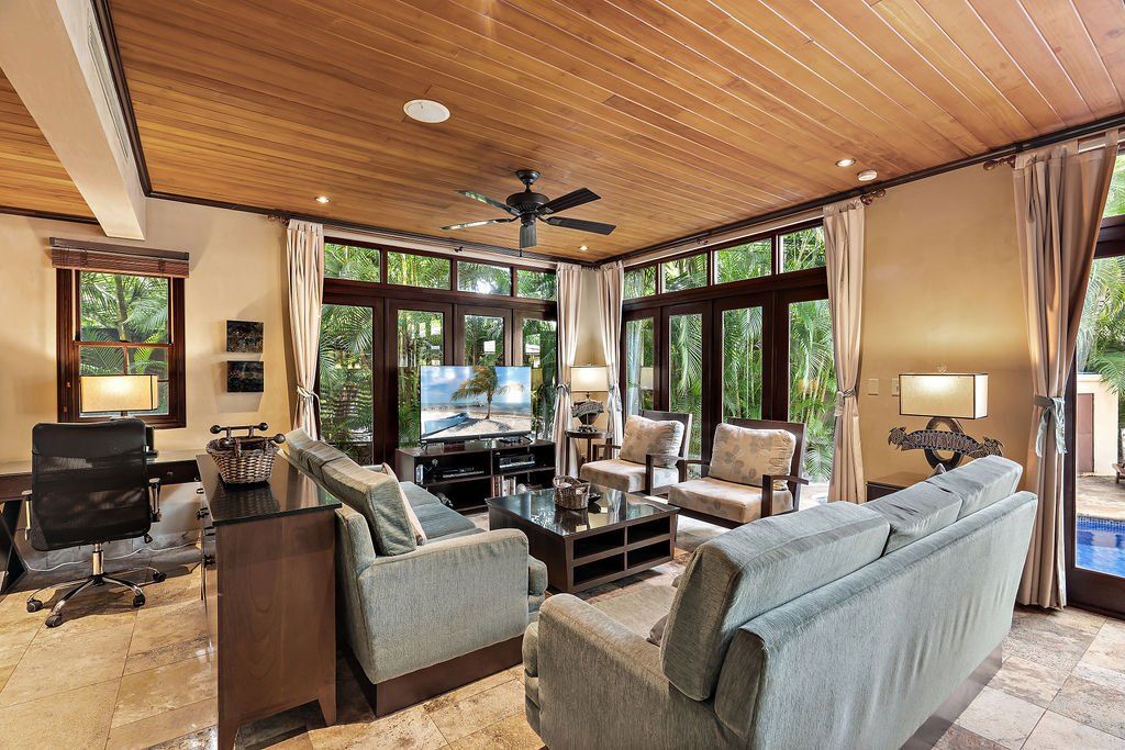 Bright living room with gray sofas, wood ceiling, fireplace, and large windows looking outside