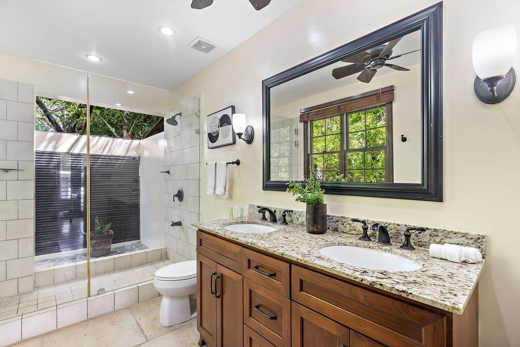 Modern bathroom with glass shower, freestanding tub, and wood vanity with large mirror