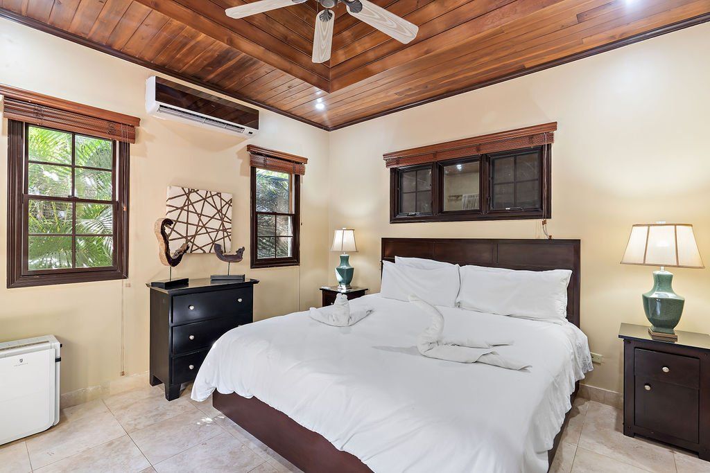 Cozy bedroom with a white bed, wooden ceiling, windows, and bedside lamps