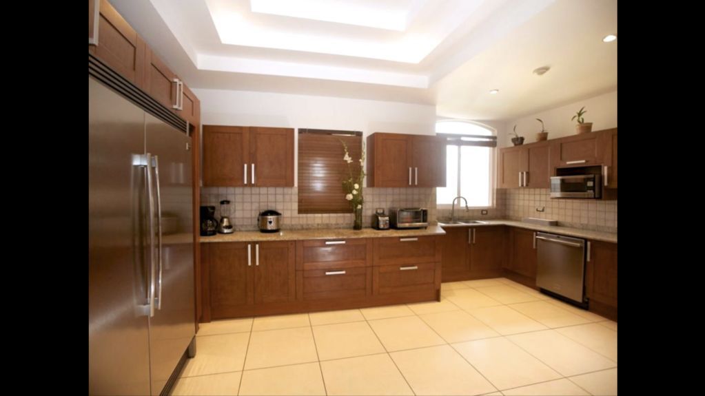 Modern kitchen with wooden cabinets, stainless steel appliances, and beige tile floor.