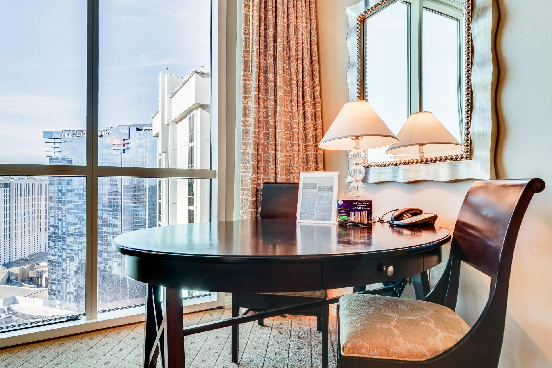 Hotel room desk by a window with city skyline and lamps