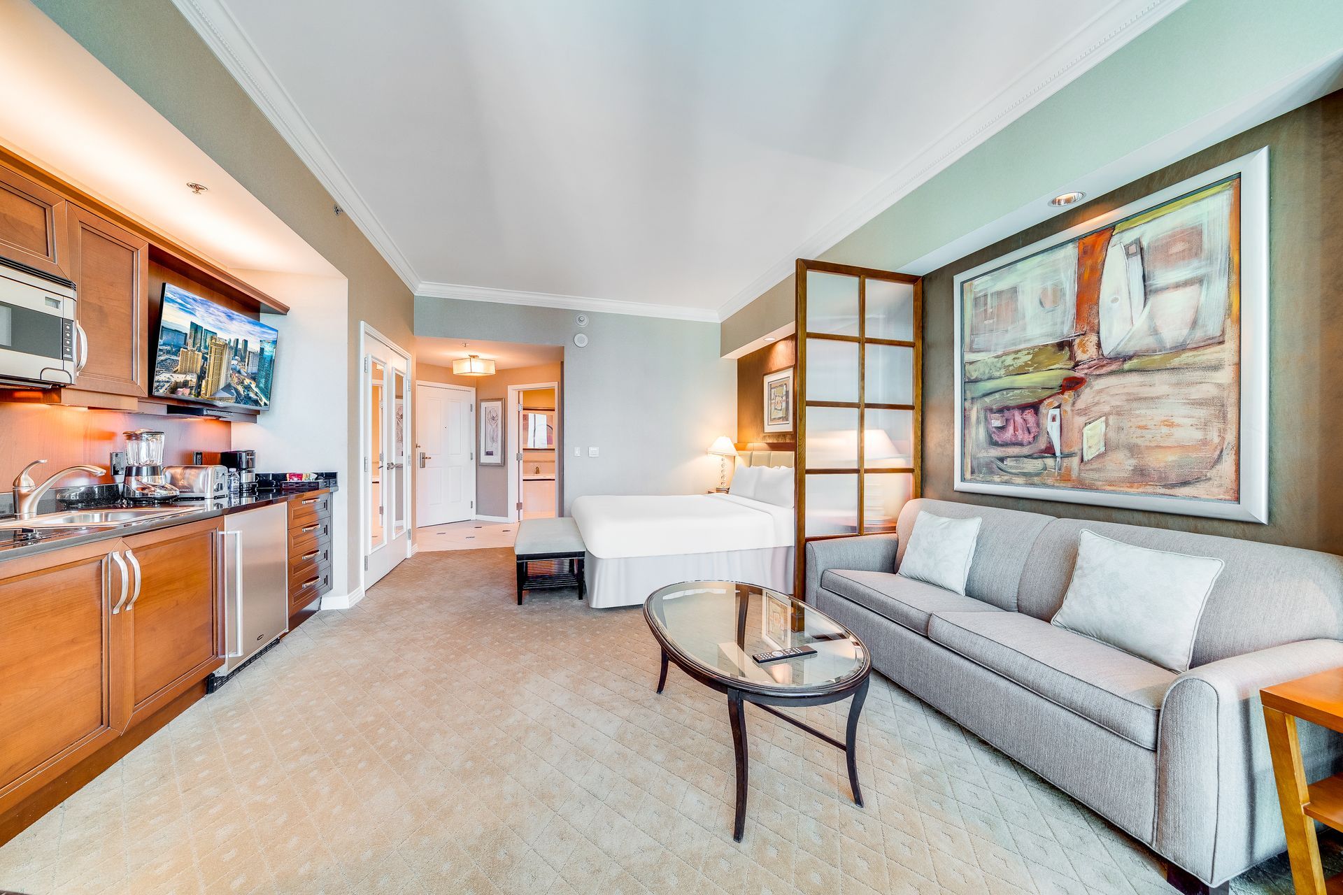 Bright studio apartment with sofa, coffee table, kitchen, and bed in a light gray interior