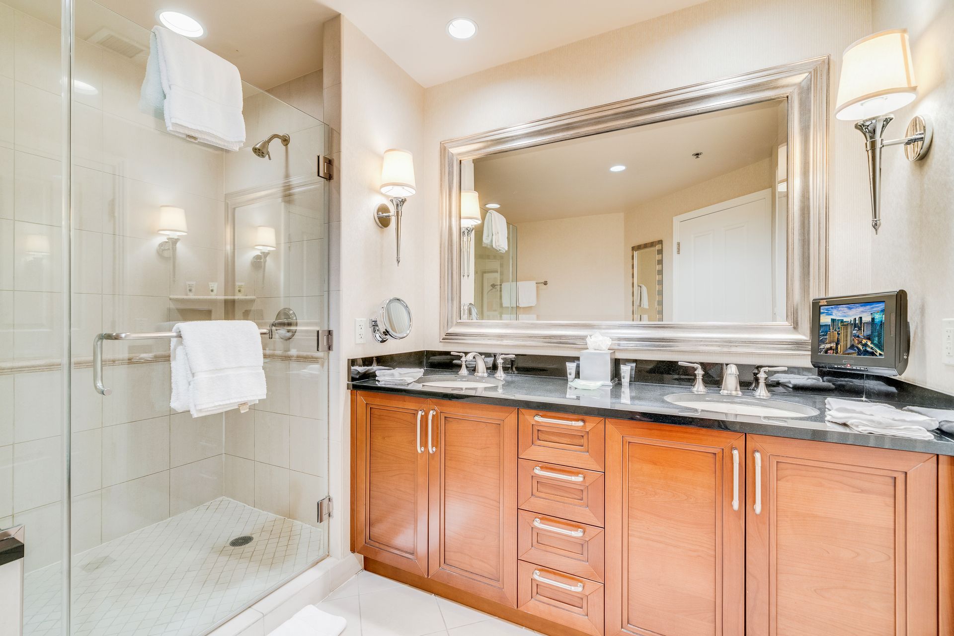 Modern bathroom with glass shower, large mirror, and wooden double vanity