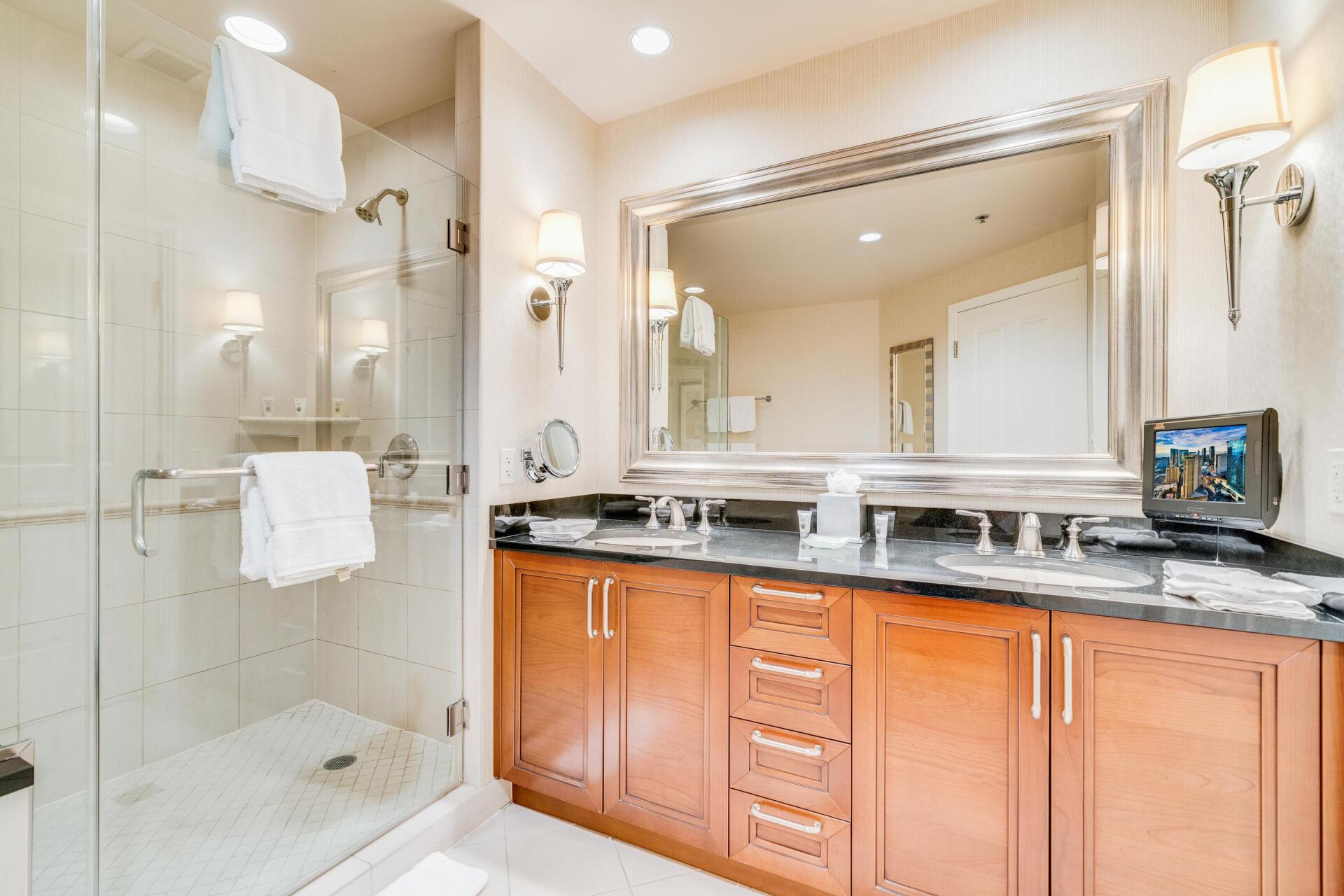 Modern bathroom with glass shower, large mirror, and wood vanity with black countertop