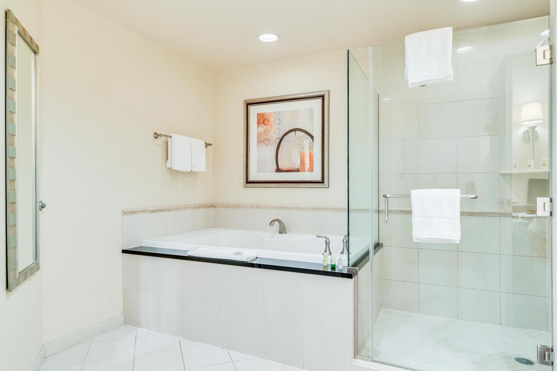 Bright modern bathroom with a soaking tub, glass shower, and white tile walls.