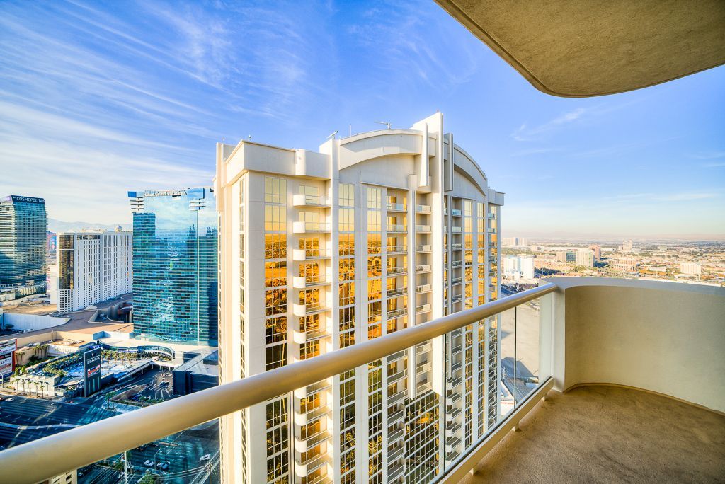 High-rise balcony view of a city skyline at sunset with tall buildings and blue sky