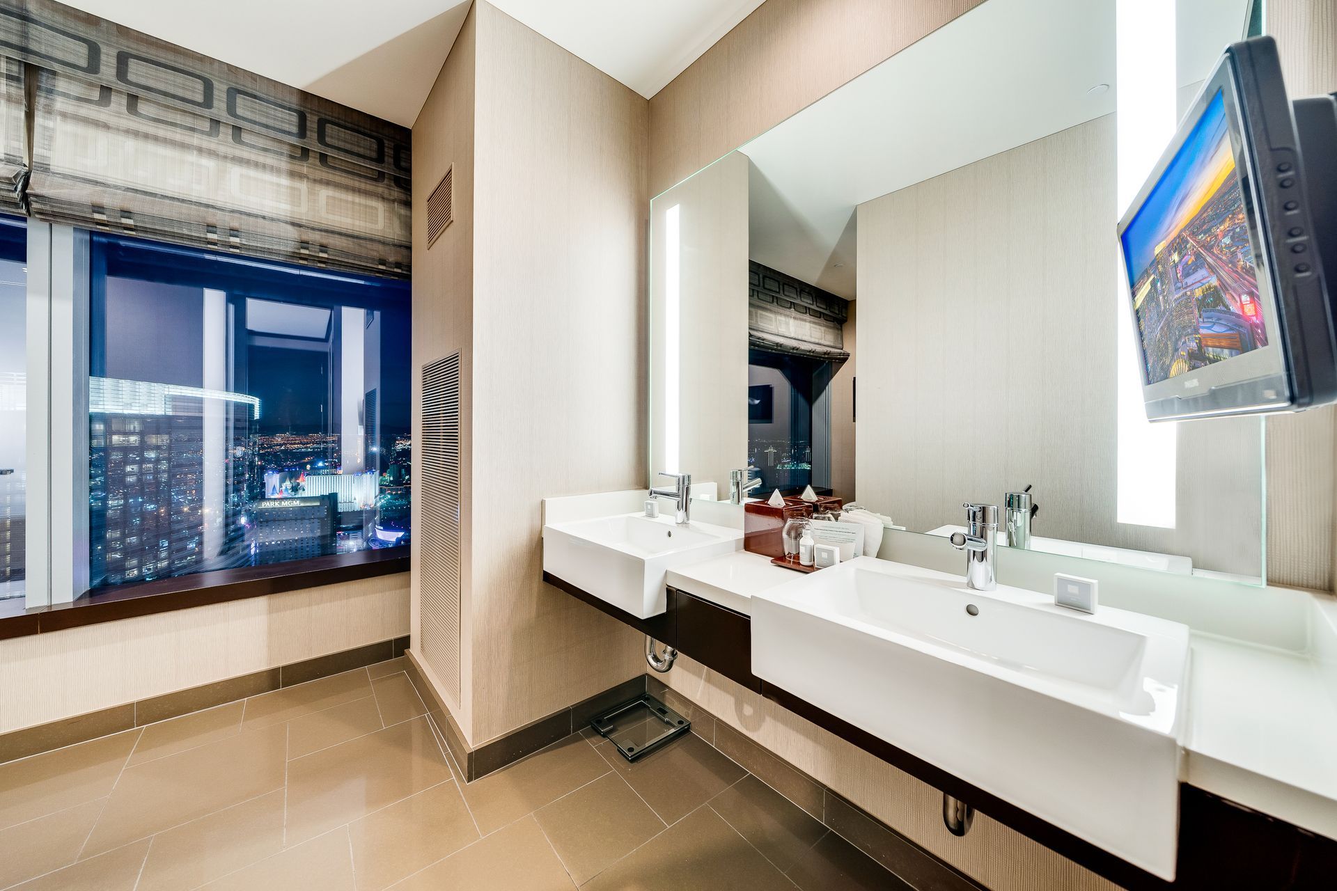 Modern bathroom with double sink vanity, large mirror, and city view through a window