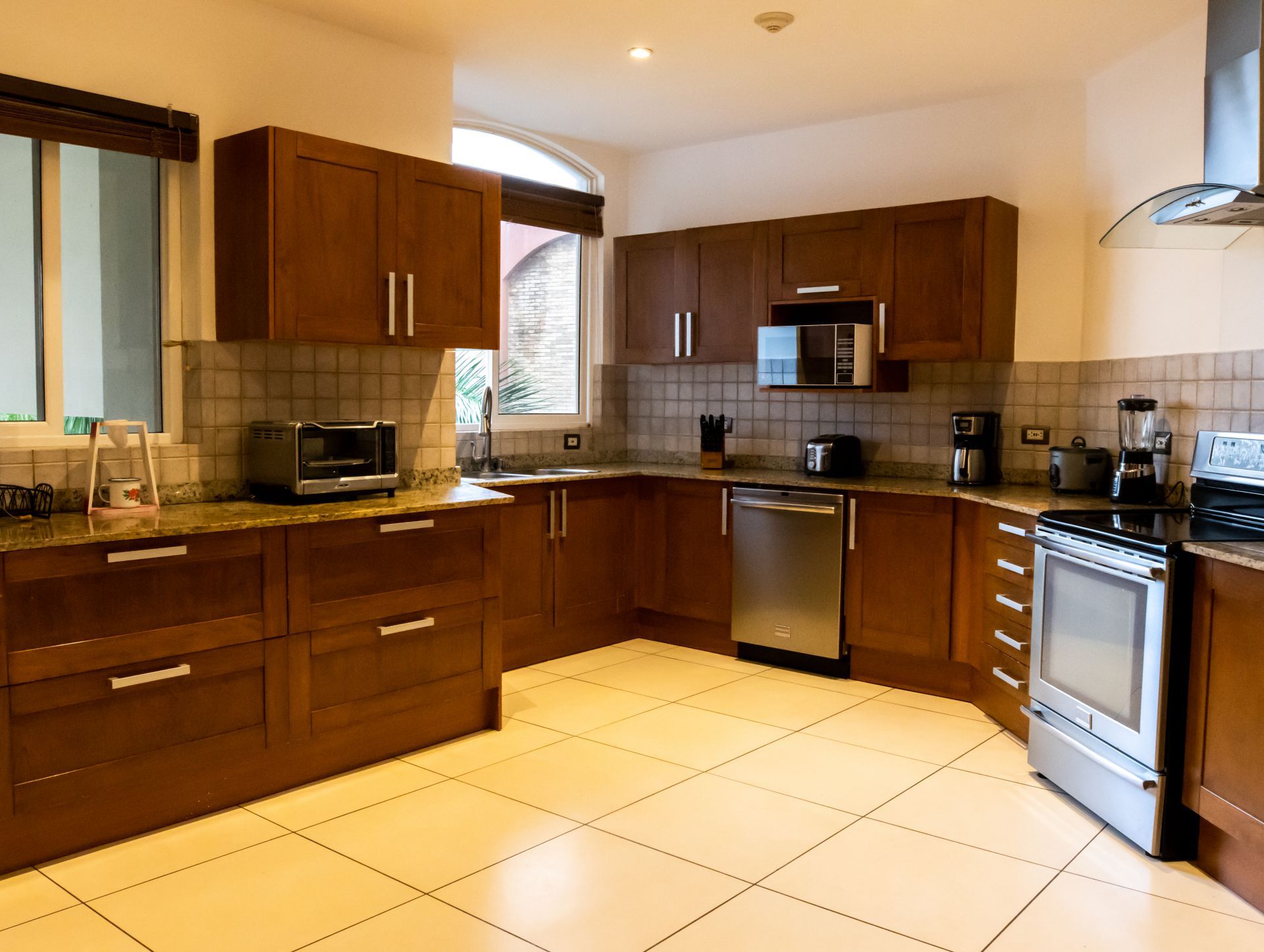 Modern kitchen with wood cabinets, stainless steel appliances, and tiled floor