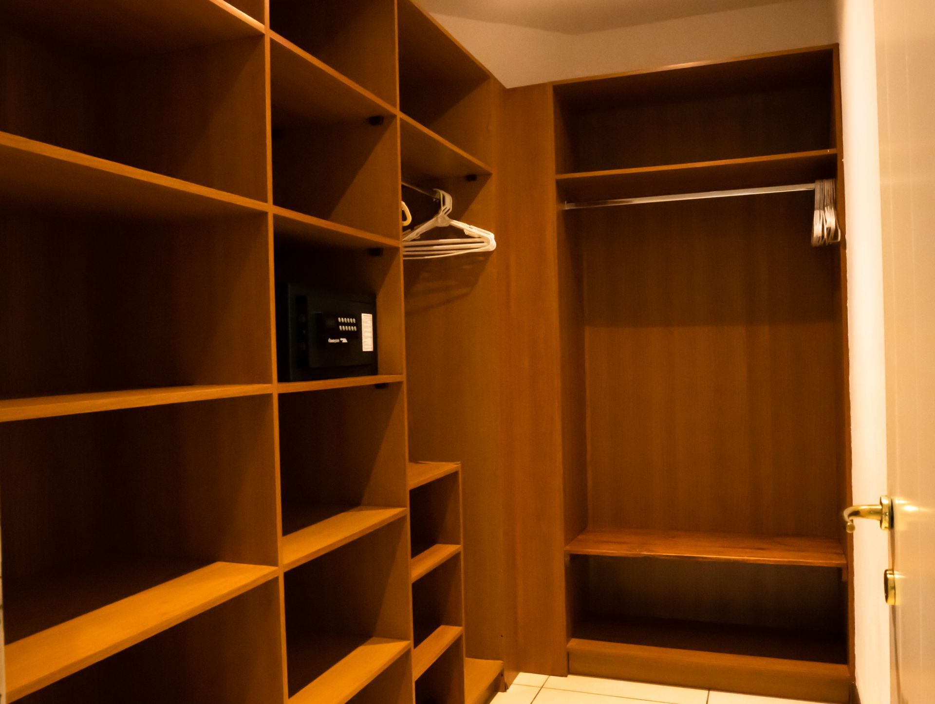 Wooden walk-in closet with shelves, hanging rod, and an open door.