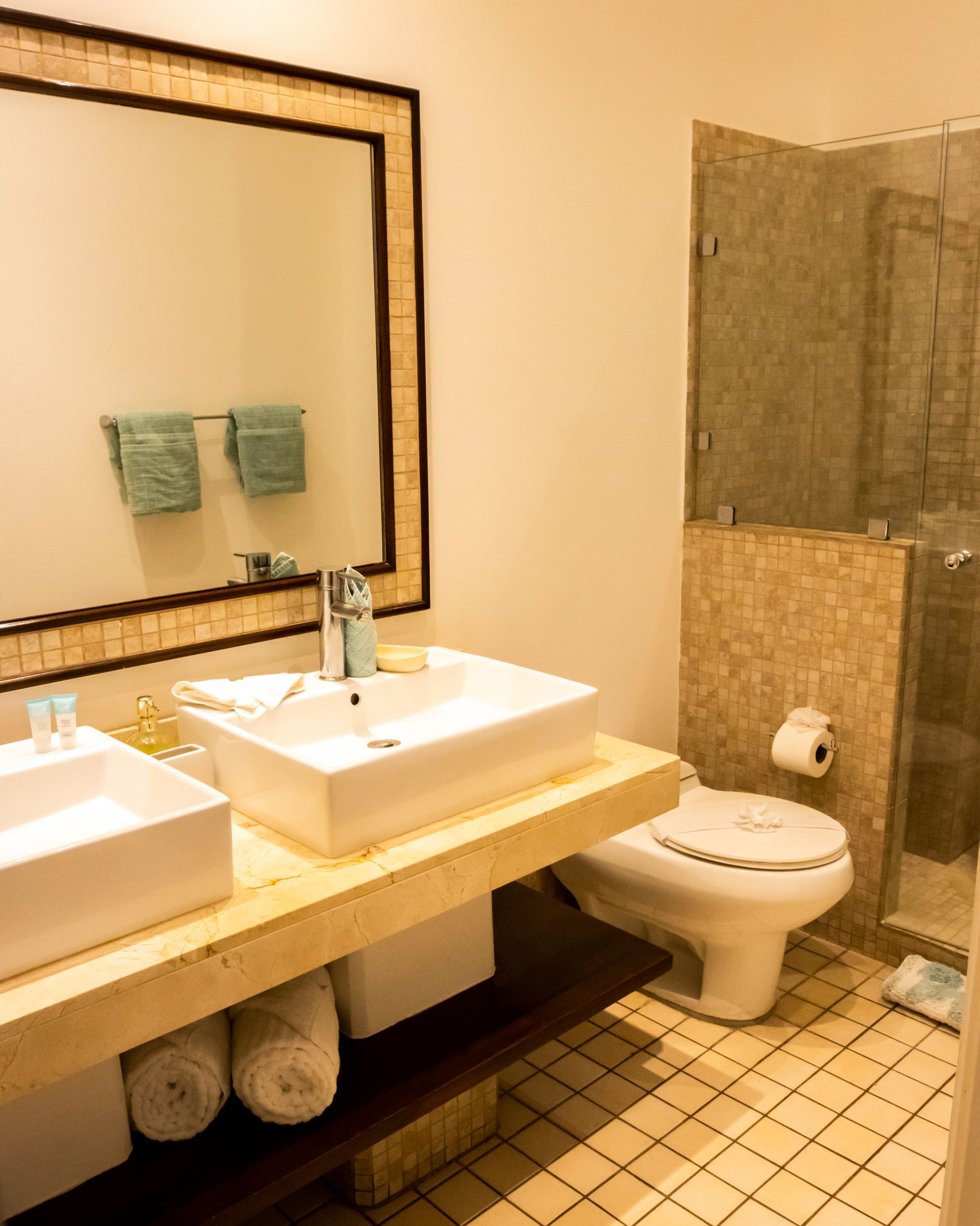 Modern bathroom with double sinks, large mirror, toilet, and tiled shower area