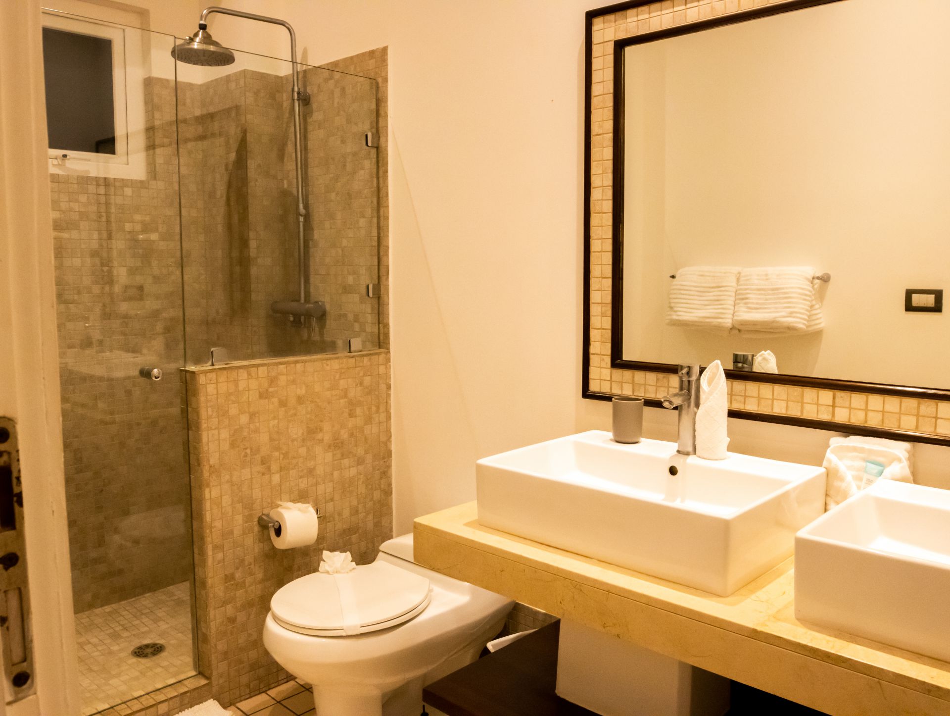 Modern bathroom with shower, toilet, double sink, and large mirror.