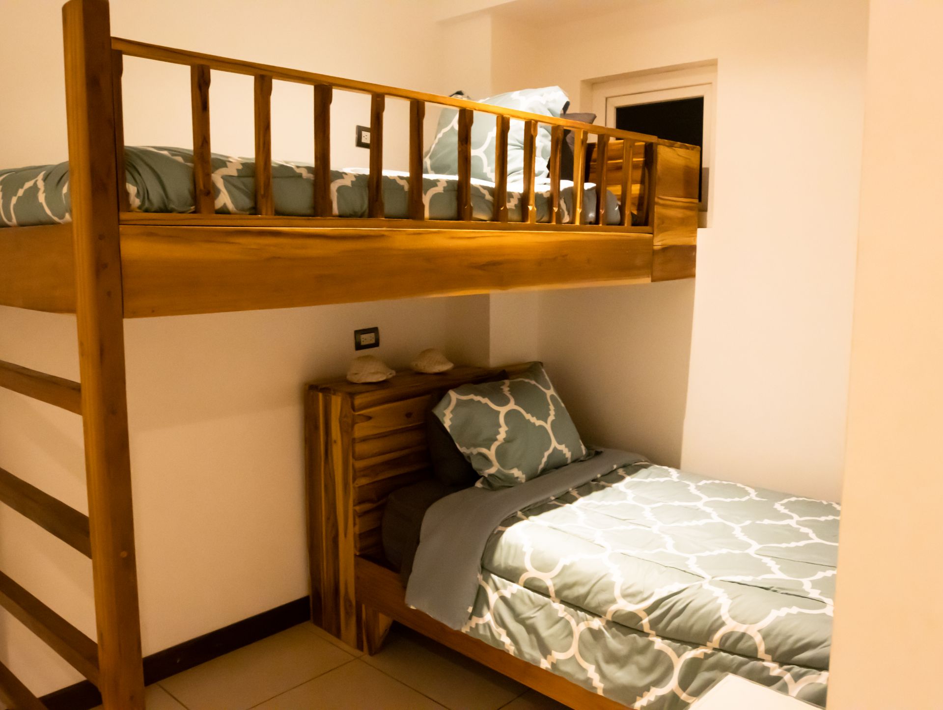 Small bedroom with a wooden bunk bed, single bed below, and blue-gray patterned bedding