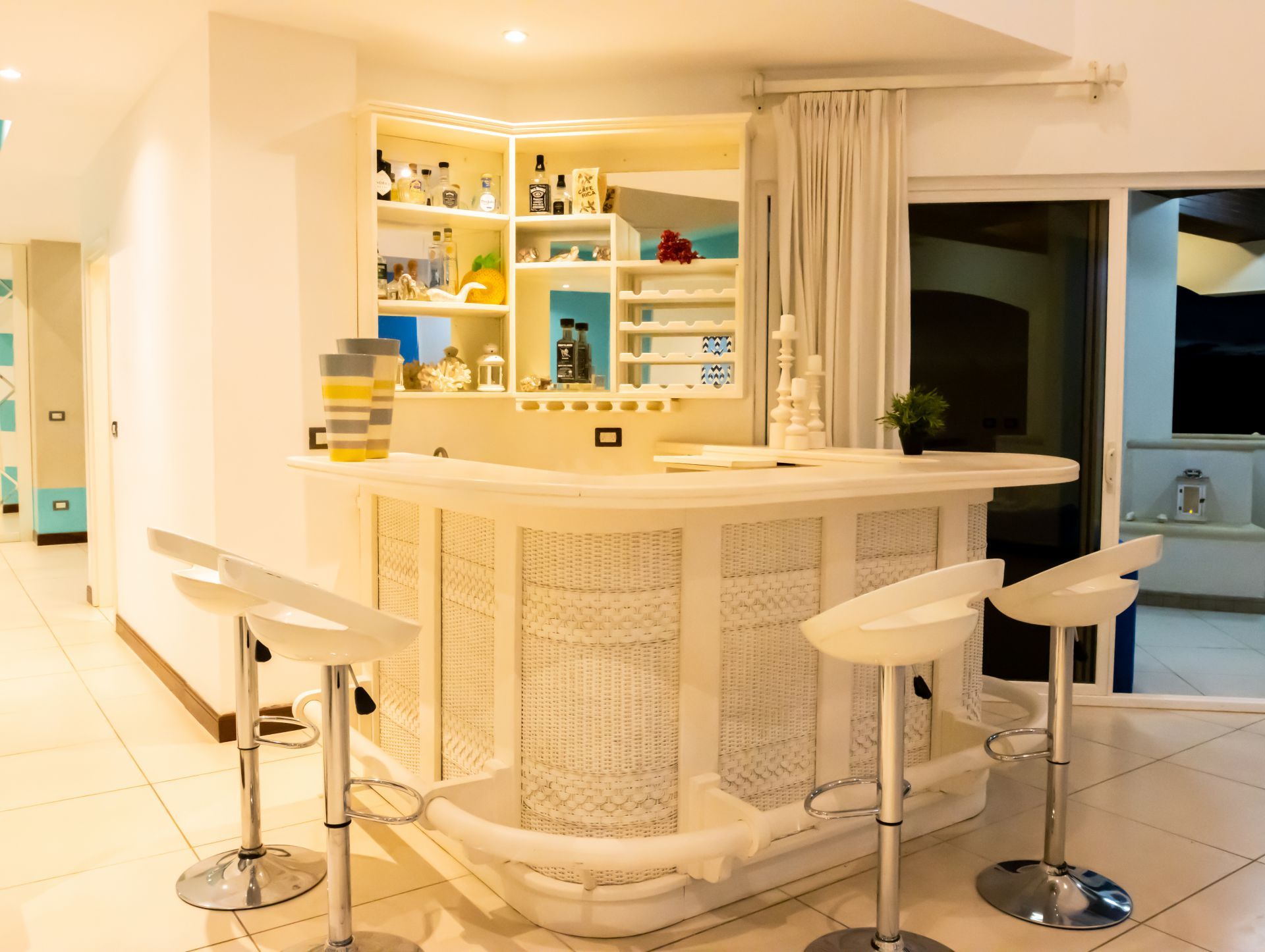 Bright white bar area with stools in a modern kitchen, lit by warm overhead lights.