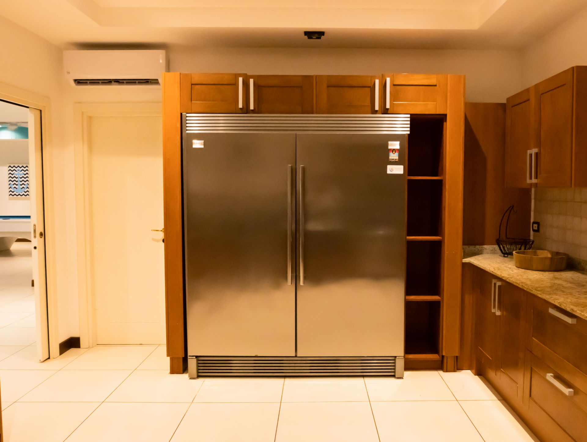 Kitchen with stainless steel double-door refrigerator between wood cabinets and granite countertop.
