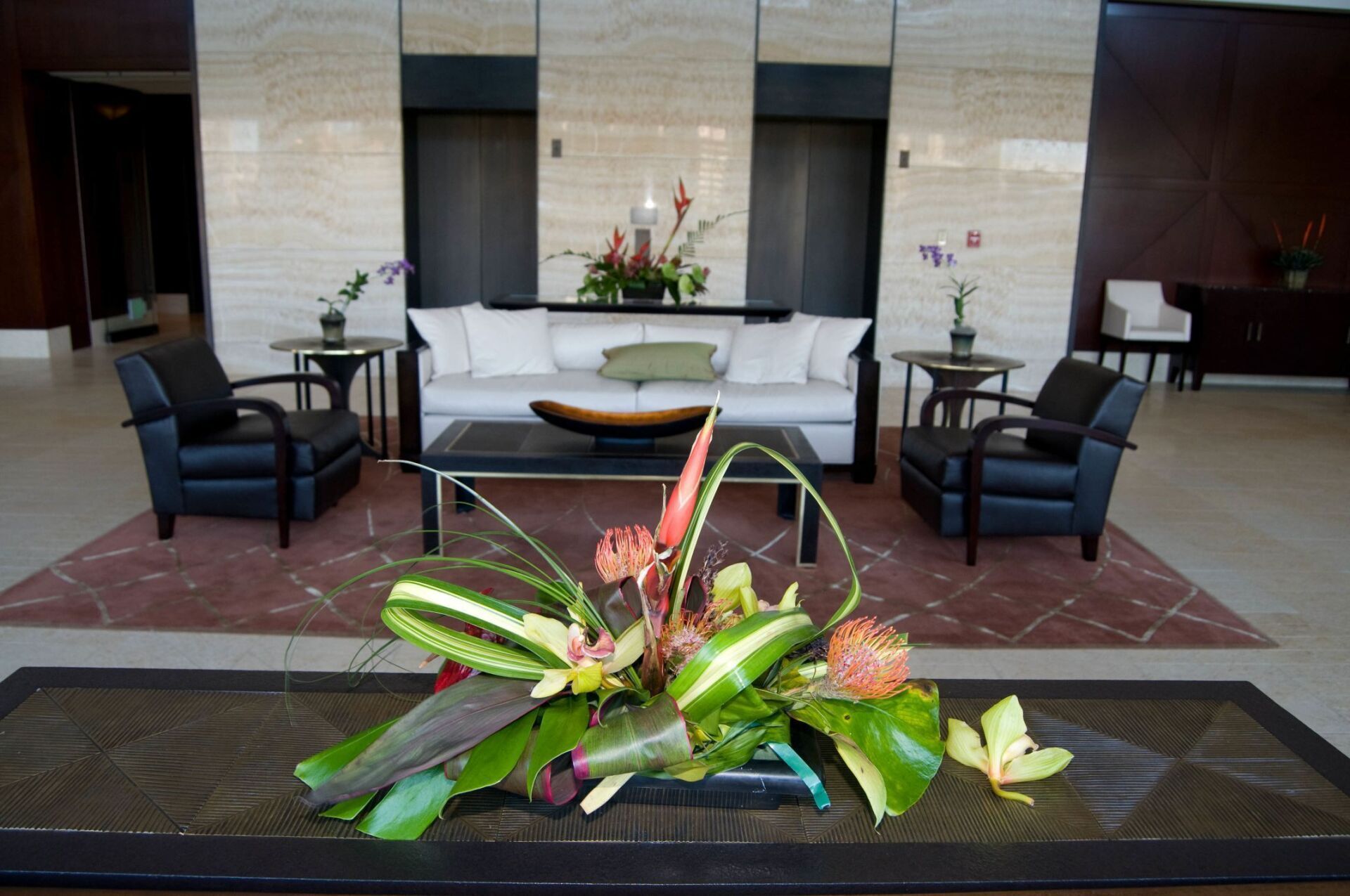 Elegant hotel lobby seating area with black chairs, white sofa, and floral arrangements