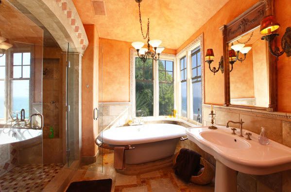 Sunlit bathroom with a freestanding tub, double sink, mirror, and warm terracotta walls